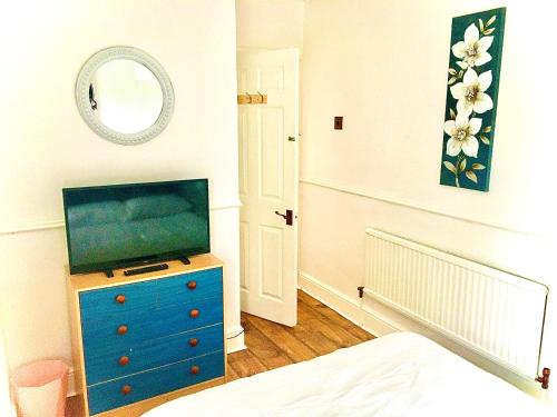 a bedroom with a blue dresser with a television on it at The Washington Sleeps 10 people park 4 cars in Bristol