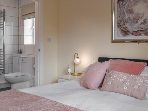 a bedroom with a bed with pink pillows and a toilet at South Carvan View in Tavernspite