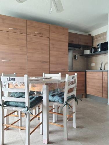 une cuisine avec une table en verre et deux chaises dans l'établissement Au bord de la plage du Grazel, à Gruissan
