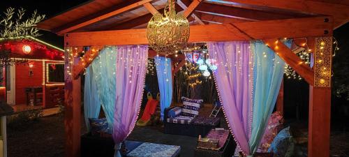 a gazebo with purple and blue curtains and lights at Refugio madera estilo árabe con estatuas, estanques y un pequeño zoo in Albacete