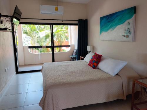 a bedroom with a bed and a large window at Cabañas Puerto Morelos in Puerto Morelos