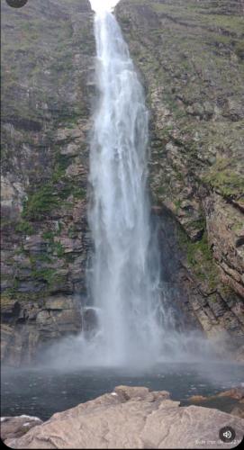 a waterfall on the side of a mountain with water at Pousada Filhos da Canastra in Vargem Bonita