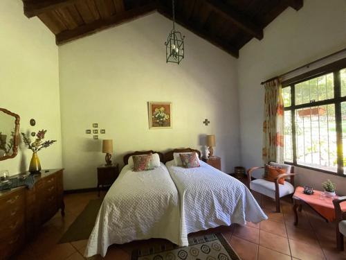 a bedroom with a bed and a chair and a window at Casa San Miguel in Antigua Guatemala