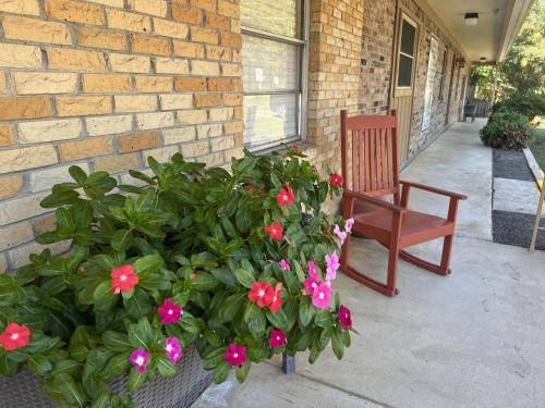 um alpendre com um banco e uma planta com flores cor-de-rosa em JI7, A Queen Guest Room at the Joplin Inn at entrance to the resort Hotel Room em Mount Ida