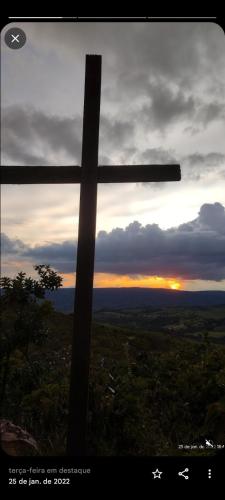 a cross in the foreground with the sunset in the background at Pousada Filhos da Canastra in Vargem Bonita