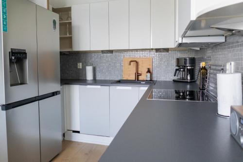 a kitchen with white cabinets and white appliances at Villa Rajaportti 1st&2nd floor Loft with lakeview and free front door parking with electric car plug in Tampere