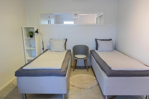 two beds in a room with a chair and a mirror at Villa Rajaportti 1st&2nd floor Loft with lakeview and free front door parking with electric car plug in Tampere