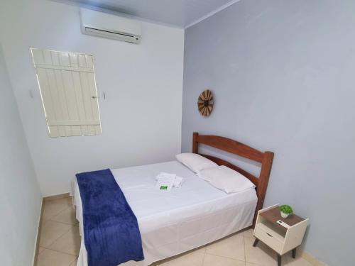 a white bedroom with a bed and a clock on the wall at Casa Areal Boipeba in Ilha de Boipeba