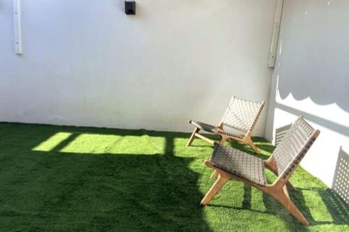 2 chaises assises sur l'herbe dans un patio dans l'établissement Casa unifamiliar FIBES, à Séville