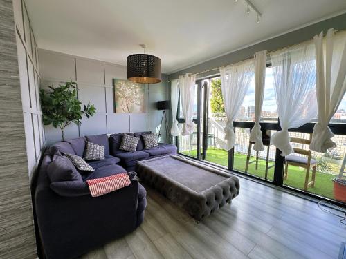 a living room with a purple couch and a large window at Luxury 2 BR Flat in Canary Wharf in London
