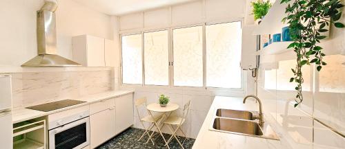 a white kitchen with a sink and a table at Your home in Valencia in Valencia