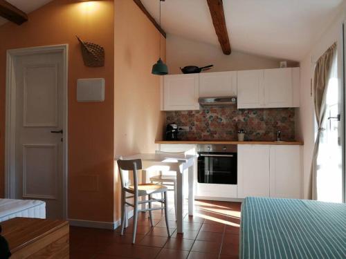 a kitchen with white cabinets and a table and chairs at CASA LITA con terrazzo in Ravenna
