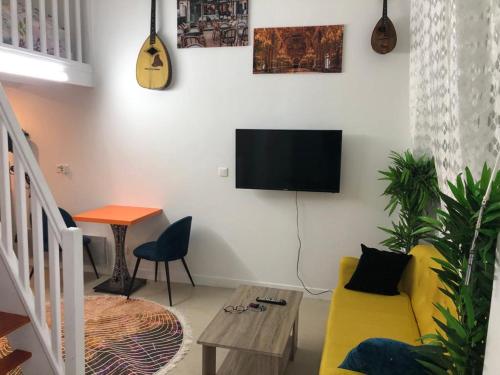 Il comprend un salon doté d'un canapé jaune et d'une télévision à écran plat. dans l'établissement Studyo cosy 400 metre sacre ceour, à Paris
