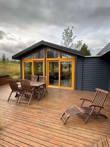 a deck with chairs and a table and a house at Luxury cottage located in the Golden Circle, mountain view! in Laugarvatn