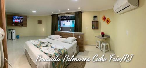 a bedroom with a bed and a television in it at Pousada Palmares in Cabo Frio