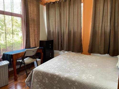 a bedroom with a bed and a desk and a window at Villas JABEL TINAMIT in Panajachel