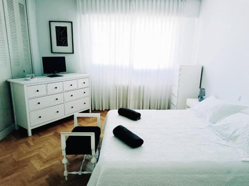 a bedroom with a white bed and a white dresser at Casa de Mirtha in Madrid