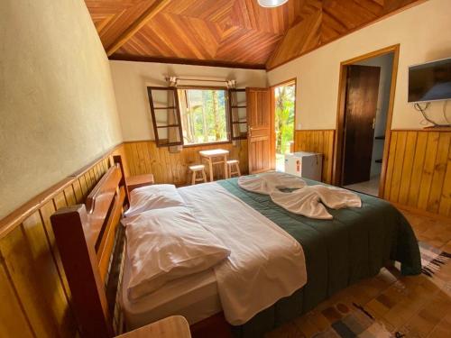 ein Schlafzimmer mit einem großen Bett in einem Zimmer in der Unterkunft Pousada Algama in Visconde De Maua