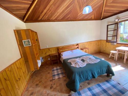 a bedroom with a bed in a room with wooden ceilings at Pousada Algama in Visconde De Maua