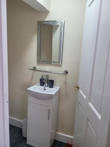 a white bathroom with a sink and a mirror at Nest Studio in Tilehurst