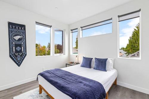 a white bedroom with a bed and two windows at The Sweet Suite in the North in Seattle