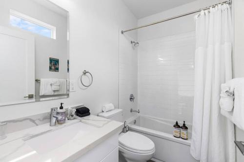 a white bathroom with a tub and a toilet and a sink at The Sweet Suite in the North in Seattle