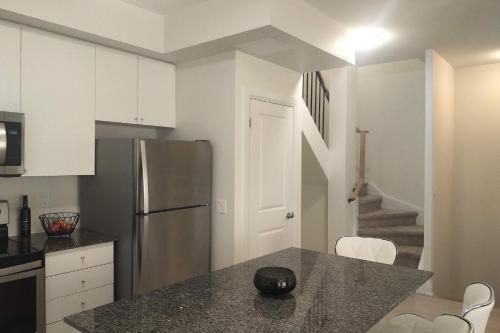 a kitchen with a stainless steel refrigerator and white cabinets at GGP Boutique Townhome in Vaughan