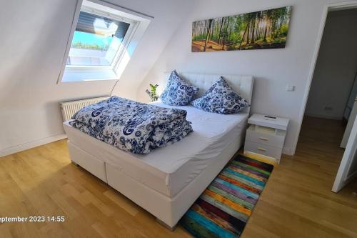 Modernes Apartment mit 3 Zimmern في كارلسروه: غرفة نوم مع سرير ووسائد زرقاء وبيضاء