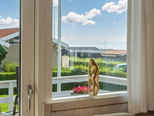 a window with a statue of a woman in a flower pot at 6 person holiday home in Juelsminde in Sønderby