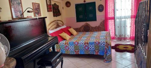een kamer met een bed en een piano in een kamer bij Punta Family House in San Giovanni la Punta