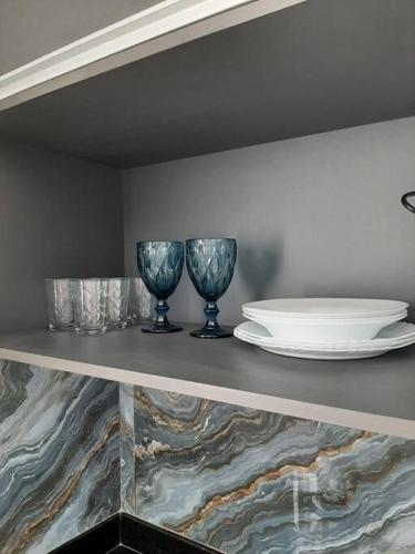 a shelf with three glasses and a plate on it at Luxo e conforto in Goiânia
