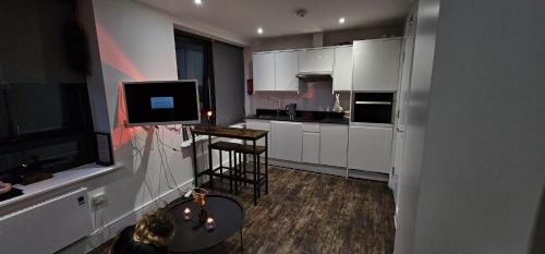 a kitchen with white cabinets and a table and a television at Cosy studio flat in North London in London