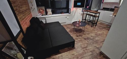 uma sala de estar com um sofá preto e uma mesa em Cosy studio flat in North London em Londres