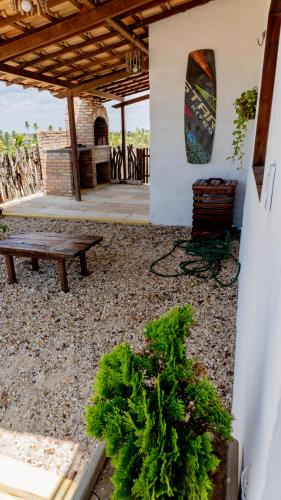 a patio with a bench and a surfboard on a wall at Casa da Duna in Tatajuba