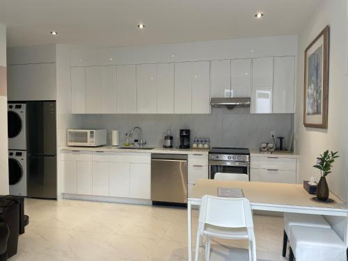 a kitchen with white cabinets and a table and chairs at Brand new 1Queenbed family suite near UBC in Vancouver