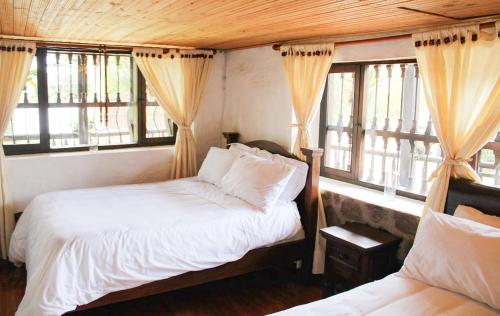 a bedroom with two beds and two windows at Hospedaje Villa Eucalyptus in Nobsa