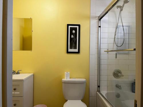 uma casa de banho amarela com um WC e um chuveiro em Beddington private room close Airport! em Calgary