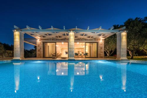 a swimming pool in front of a house at night at Avra Luxury Villa & Spa in Keri