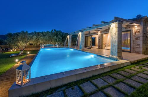 a swimming pool in the backyard of a house at night at Avra Luxury Villa & Spa in Keri