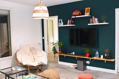 uma sala de estar com uma televisão e uma cadeira em Cosy Colour Place em Villiers-sur-Marne