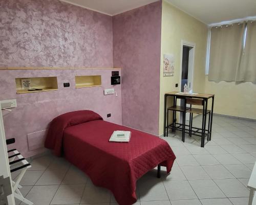 Schlafzimmer mit einem Bett mit einer roten Decke und einem Tisch in der Unterkunft HomeFamily in Lido di Ostia