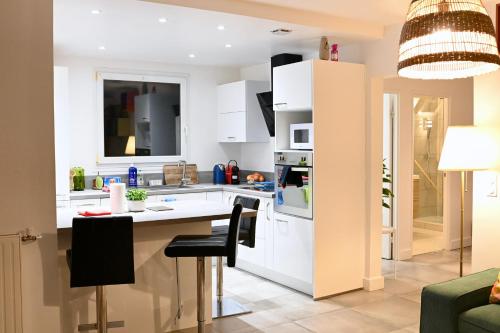 cocina con armarios blancos, mesa y sillas en Cosy Colour Place en Villiers-sur-Marne