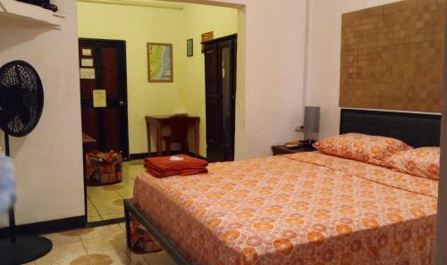 1 dormitorio con 1 cama con manta naranja en Max Rooms en San Ignacio