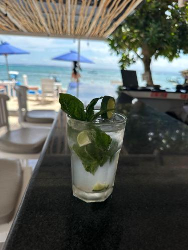 a drink with lime and mint on a table at a beach at Nusa Indah Bungalow in Nusa Lembongan