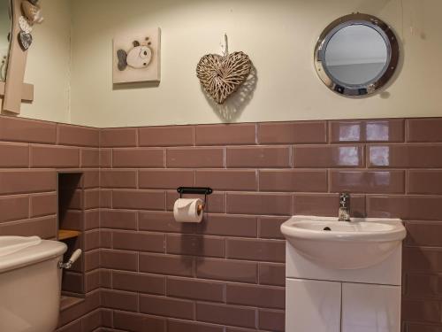 a bathroom with a toilet and a sink and a mirror at Daisys Dairy in Bishops Lydeard