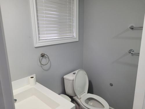 a white bathroom with a toilet and a window at Relax place in Brampton