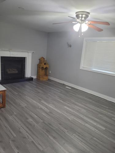 an empty living room with a ceiling fan and a fireplace at Relax place in Brampton