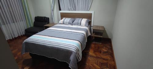 een kleine slaapkamer met een bed en een stoel bij GOLDEN DREAMS in Callampaya