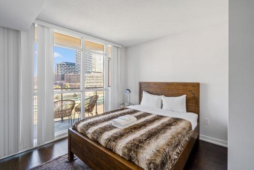 a bedroom with a bed and a large window at Family oriented Downtown Toronto 2BDRM Condo with Parking & office space in Toronto