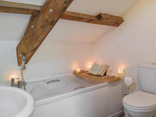 a bathroom with a bath tub with a book and candles at Yr Ysgubor - U45300 in Carmarthen